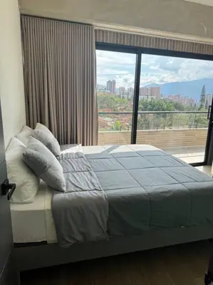 a bedroom with a bed and a large window at Apartamento 406 Poblado Cerca al CC El Tesoro in Medellín