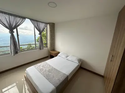 a bedroom with a bed and two large windows at Sector Tranquilo y Central, Excelente Vista in Manizales