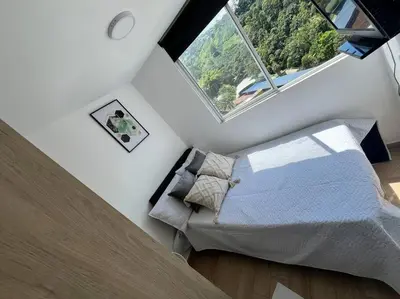 an attic bedroom with a bed and a large window at Apartamento Piscina sabaneta Medellín 20 minutos Poblado in Envigado
