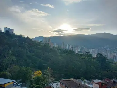 a view of a city with the sun setting on a hill at Apartamento Piscina sabaneta Medellín 20 minutos Poblado in Envigado