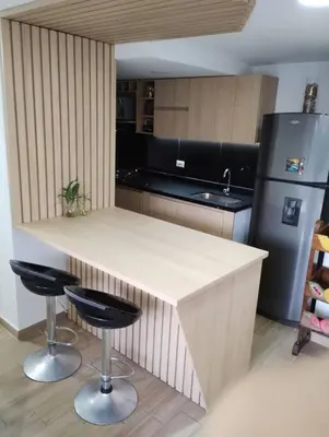 a kitchen with a counter with two stools and a refrigerator at Apartamento Piscina sabaneta Medellín 20 minutos Poblado in Envigado