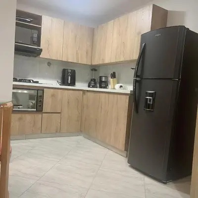a kitchen with a black refrigerator and wooden cabinets at Diamante 204 in Guatapé