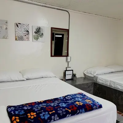 a bedroom with two beds and a mirror at Hotel Villa Nueva Comfort in Medellín