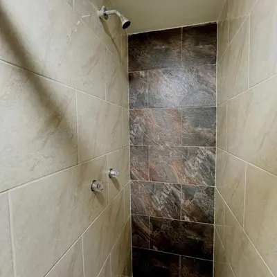 a bathroom with a shower with a stone wall at Hotel Villa Nueva Comfort in Medellín