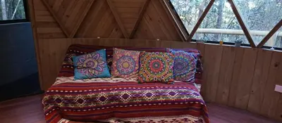 a bed with colorful pillows in a wooden room at Sanayá Domo Glamping - Santa Elena in Santa Elena