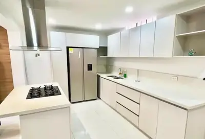 a white kitchen with a stove and a refrigerator at Apartamento Laureles con Jacuzzi cerca al primer parque in Medellín