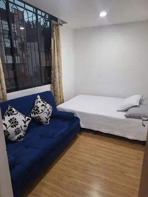 a bedroom with a bed and a blue couch at Apartamento Cerca a Primer Parque de Laureles in Medellín