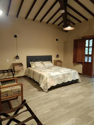 a bedroom with a large bed and a wooden floor at Finca MonteSer in Jardin
