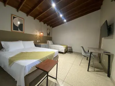 a bedroom with a bed and a table and a desk at Hotel La Vega in Concepción