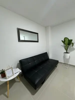 a black couch in a room with a table and a mirror at Apartamento céntrico en Medellín in Medellín