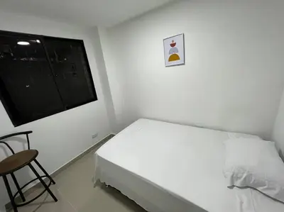 a white bedroom with a bed and a window at Apartamento cerca al centro en Medellín in Medellín
