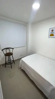 a bedroom with a bed and a chair next to a window at Apartamento cerca al centro en Medellín in Medellín