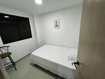 a white bedroom with a bed and a window at Apartamento cerca al centro en Medellín in Medellín