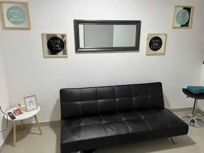 a black leather couch in a room with a mirror at Apartamento cerca al centro en Medellín in Medellín