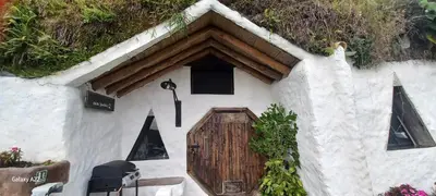 a small white building with a wooden door at Hobbit Hotel El peñol Guatapé in La Pradera