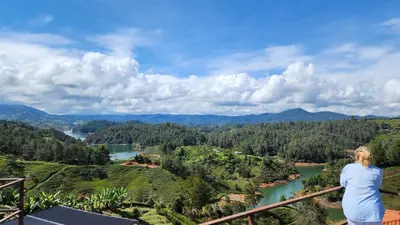 a woman standing on a balcony looking out over a river at Hobbit Hotel El peñol Guatapé in La Pradera