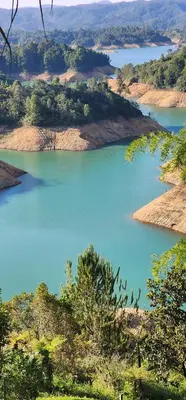 a view of a large blue lake with trees and land at Hobbit Hotel El peñol Guatapé in La Pradera