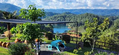 two people standing in a garden with a view of a lake at Hobbit Hotel El peñol Guatapé in La Pradera