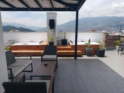 a balcony with chairs and a tub on a roof at Laureles Penthouse rooftop Suite in Medellín