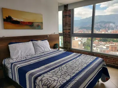 a bedroom with a bed with a view of a city at Laureles Penthouse rooftop Suite in Medellín