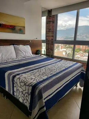 a bedroom with a bed and a large window at Laureles Penthouse rooftop Suite in Medellín