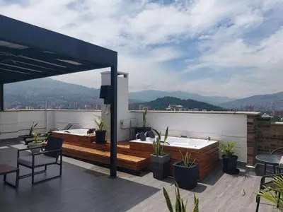 a rooftop patio with a hot tub and table and chairs at Laureles Penthouse rooftop Suite in Medellín