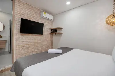 a bedroom with a white bed and a brick wall at MULATA - Provenza 3 Story Villa with Pool & Rooftop in Medellín