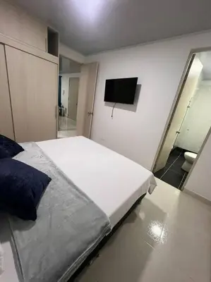 a bedroom with a large bed and a tv on the wall at Hermoso Apartamento en Belén in Medellín