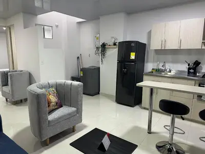 a kitchen with a chair and a table and a refrigerator at Hermoso Apartamento en Belén in Medellín