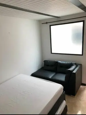 a room with a bed and a black leather couch at Apartamento en Guatapé por noches in Guatapé