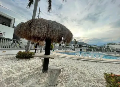 a straw umbrella on the beach next to a pool at Casa Lupita Hermoso apartasol in Santa Fe de Antioquia