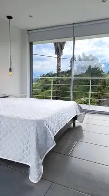 a white bed in a room with a large window at Casa Campestre Bellavista in Villamaría