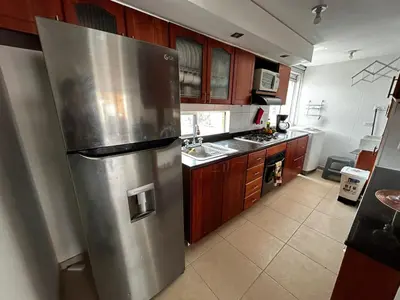 a kitchen with a stainless steel refrigerator and wooden cabinets at Bright and Modern Medellin Apartment in Medellín