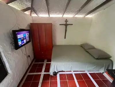a small room with a bed and a cross on the wall at Villa Arte Rustico in Ciudad Bolívar
