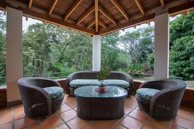 a porch with wicker chairs and a table on a porch at Tres Lagos Hotel in San Jerónimo