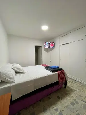 a bedroom with a bed with a tv on the wall at Entre Jardines in Medellín