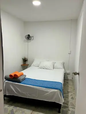 a bedroom with a white bed with an orange towel on it at Entre Jardines in Medellín