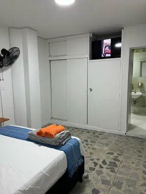 a bedroom with a bed and a bathroom with a tv at Entre Jardines in Medellín