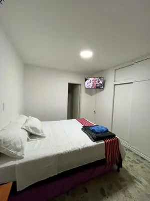 a bedroom with a bed and a tv on the wall at Entre Jardines in Medellín
