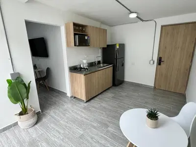a small kitchen with a table and a refrigerator at Dream apt close to Unicentro - spacious - with AC in Medellín