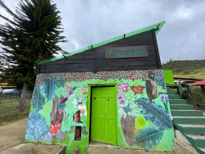a small building with a green door and flowers at Camping tipo eco-confort Refugio Lancaster in Urrao