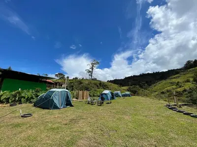 a group of tents in a field with a hill at Camping tipo eco-confort Refugio Lancaster in Urrao