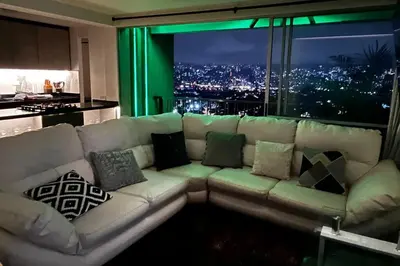 a living room with a white couch with pillows at Mirador la casa del cóndor 3 habitaciones in Itagüí