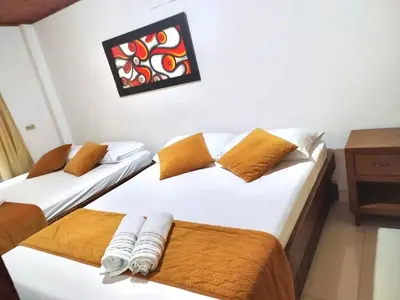 two twin beds in a room with a table at Hospedaje Casa Silvana in Jardin
