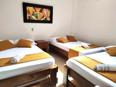 three beds in a room with a painting on the wall at Hospedaje Casa Silvana in Jardin