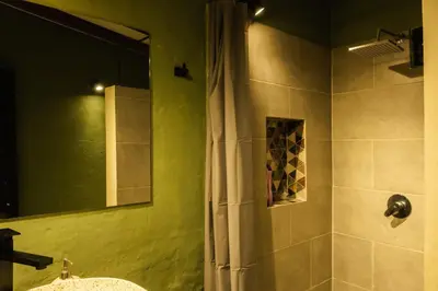 a bathroom with a shower with a sink and a mirror at Peaceful rustic cabin steps from town in Jericó