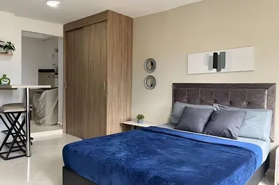 a bedroom with a blue bed and a kitchen at 9804 · 9804 Loft Env. good view local experience confort in Envigado