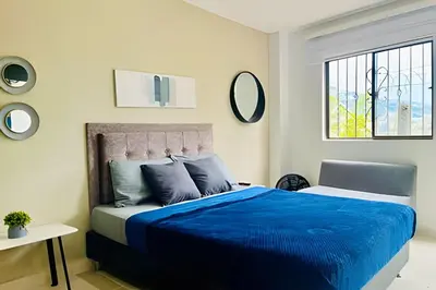 a bedroom with a bed with blue sheets and a window at 9804 · 9804 Loft Env. good view local experience confort in Envigado