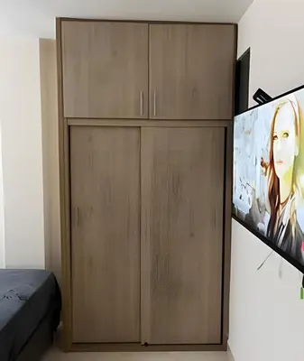 a bedroom with wooden cabinets and a flat screen tv at 9904 Acogedor y cómodo aparta estudio dotado in Envigado