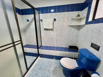 a bathroom with a blue toilet and a shower at Casa Tradicional Remodelada en Envigado con Patio in Envigado